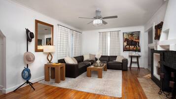 A living room with a fireplace, a ceiling fan, and a large mirror.