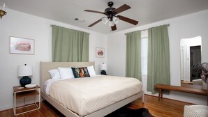 A bedroom with a bed, a nightstand, a lamp, a ceiling fan, and a mirror. - Choosing Texas (Amarillo)