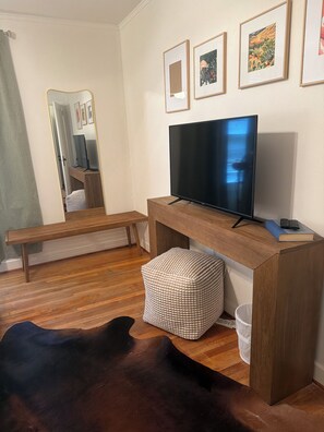 A modern living room with a flat-screen TV, wooden bench, ottoman, and a cowhide rug. - Choosing Texas (Amarillo)