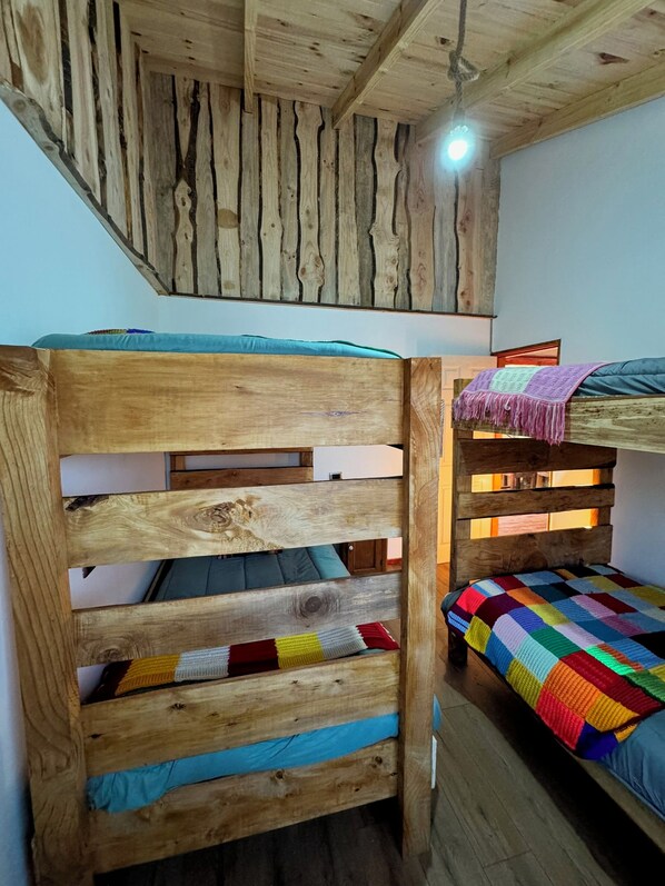 A bunk bed with a wooden headboard and a colorful quilt.