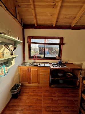 A compact kitchen with wooden cabinets, a sink, a window with a view, and a stove.