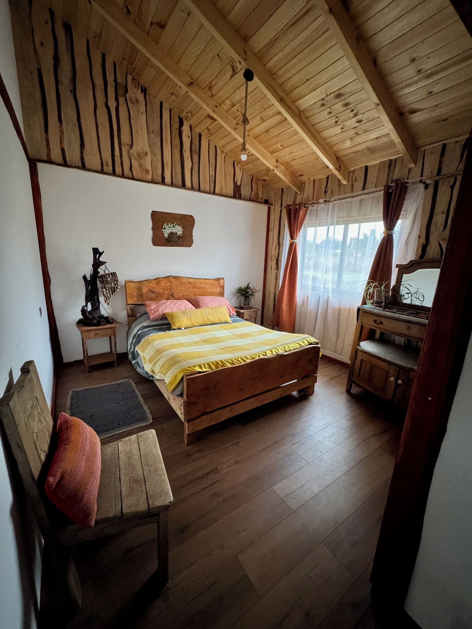 Une chambre à coucher rustique avec un lit en bois, un banc, une table de chevet et un miroir.