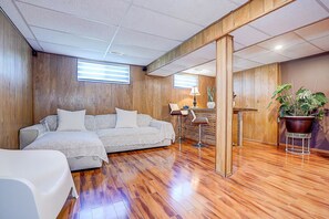Une pièce avec un plancher en bois, un canapé, une chaise, une petite table et une plante en pot.
