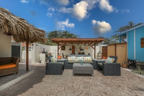 An outdoor patio with a thatched roof, a covered seating area, and a stone-tiled floor. - Luxury Noord Oasis Near Palm Beach: 4BR/4BA Villa w/ Pool – 15 Min Walk to Beach (Noord)