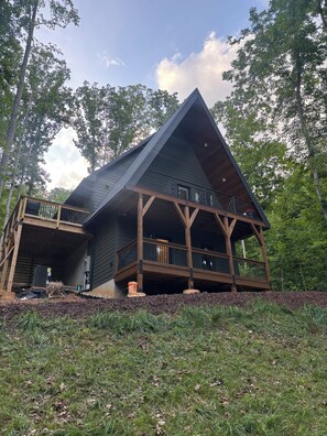 A large, modern house with a prominent triangular roof, a wooden deck, and a covered porch area. - A frame cabin (Swannanoa)