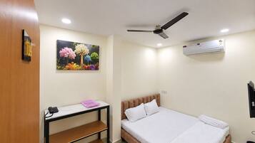 Habitación de hotel con una cama, un escritorio con teléfono, ventilador de techo y aire acondicionado.