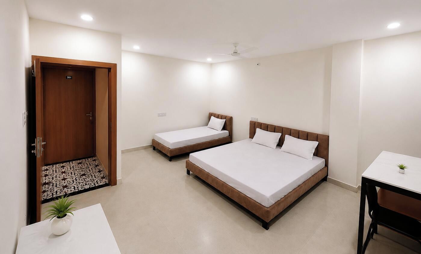 A hotel room with two beds, a desk, a chair, a ceiling fan, and a door.