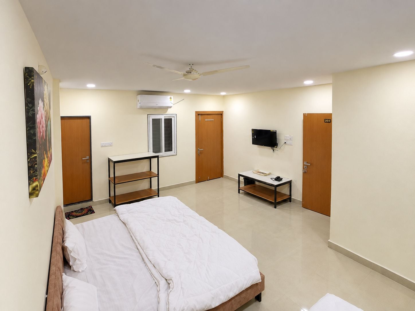 Ein Schlafzimmer mit einem Bett, einem Schreibtisch, einem Fernseher und einem Deckenventilator.