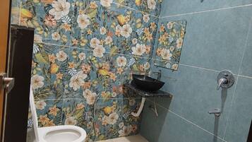 Un baño con inodoro, lavamanos, ducha y un cubo azul.