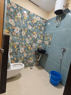 Un baño con inodoro, lavamanos, ducha y un cubo azul.