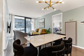 Een moderne eetruimte met een grote tafel, stoelen en een bijzondere kroonluchter.