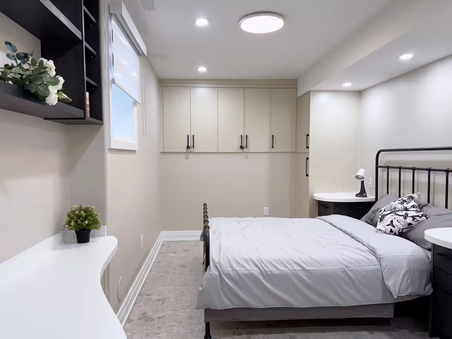 A bedroom with a bed, bedside table, lamp, and a small potted plant.