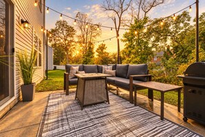 An outdoor patio with a sofa, tables, and string lights. - Arcade | Foosball | Fire Table Patio | West Akron (Akron)