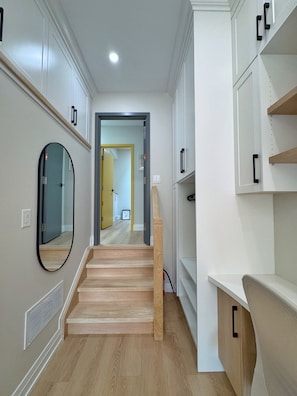 Un intérieur moderne avec un escalier en bois, des meubles blancs et un miroir.