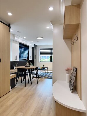 Eine moderne Küche mit Essbereich, Holzschränken und einem großen Fenster.