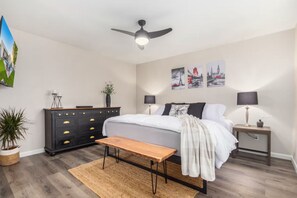 Ein Schlafzimmer mit einem Bett, Nachttischen, einem Deckenventilator und Wandbildern.