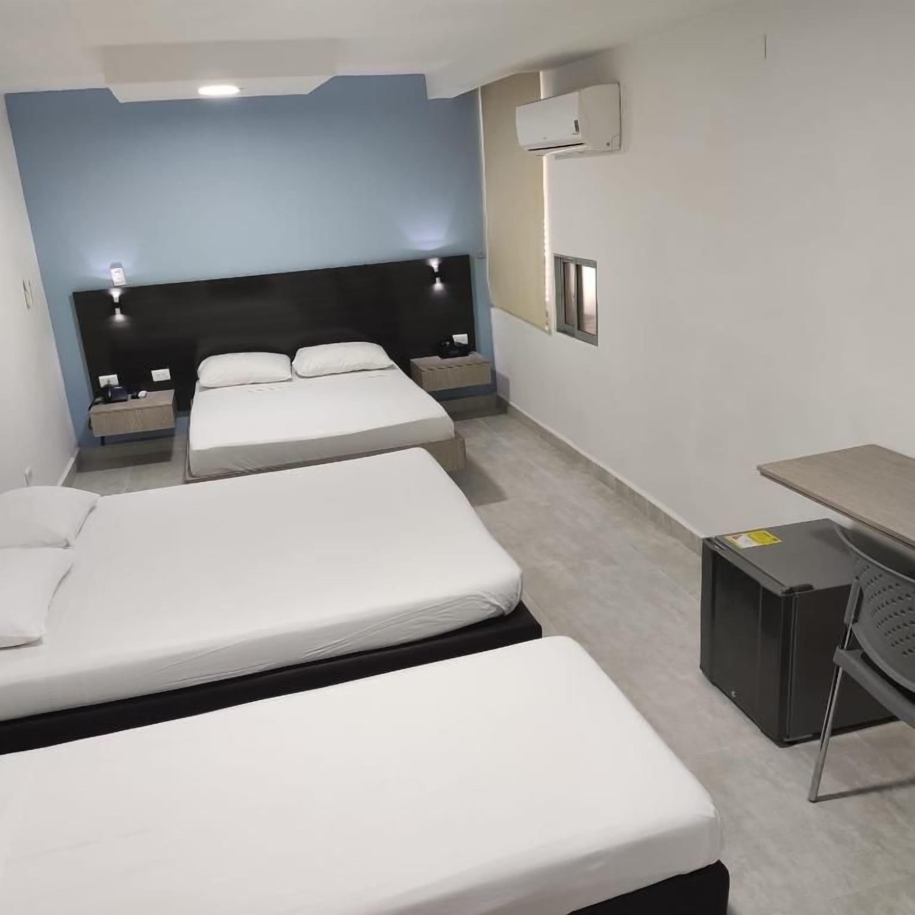 A hotel room with two beds, a desk, and a chair.