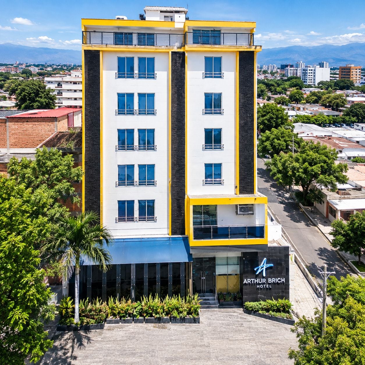 Un hôtel à plusieurs étages, doté d’une façade moderne, avec une entrée imposante et une enseigne indiquant « Hôtel Arthur Brich ».