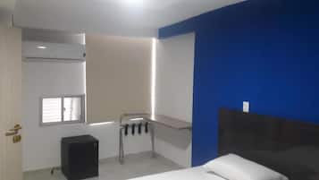 Un dormitorio con cama, una mesita de noche pequeña, ventana, calefactor y aire acondicionado instalado en la pared.