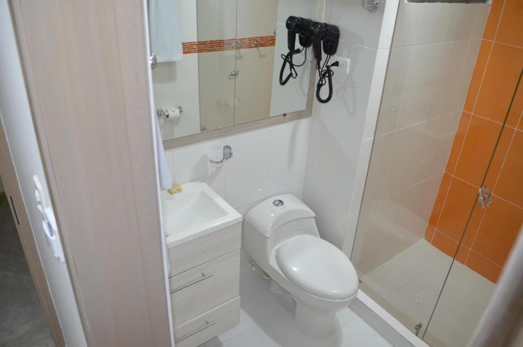 A bathroom with a toilet, sink, and a shower area.