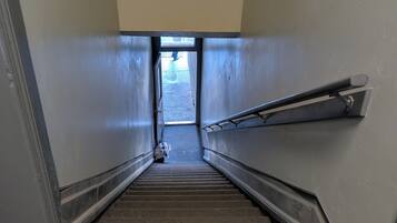 Uma escada estreita com corrimão de um lado e uma porta no topo.