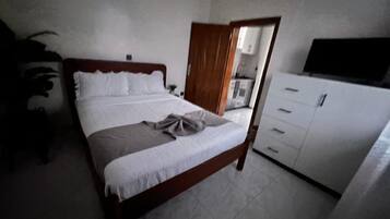 A bedroom with a bed, a wardrobe, and a desk.