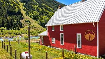 Un bâtiment rouge avec un toit en métal, entouré d’un chemin de gravier et de fleurs jaunes.