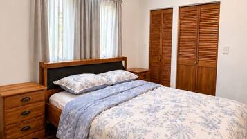 Une chambre à coucher avec un lit, des tables de chevet en bois, une lucarne et une armoire.