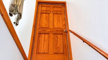 Une porte en bois se trouve en haut d’un escalier, avec une main courante sur le côté droit.