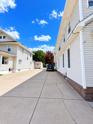 A residential street with two-story houses, a clear sky, and a car parked on the street.