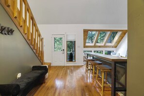 Un intérieur moderne avec un escalier en bois, un coin cuisine doté d’un bar et une grande verrière.