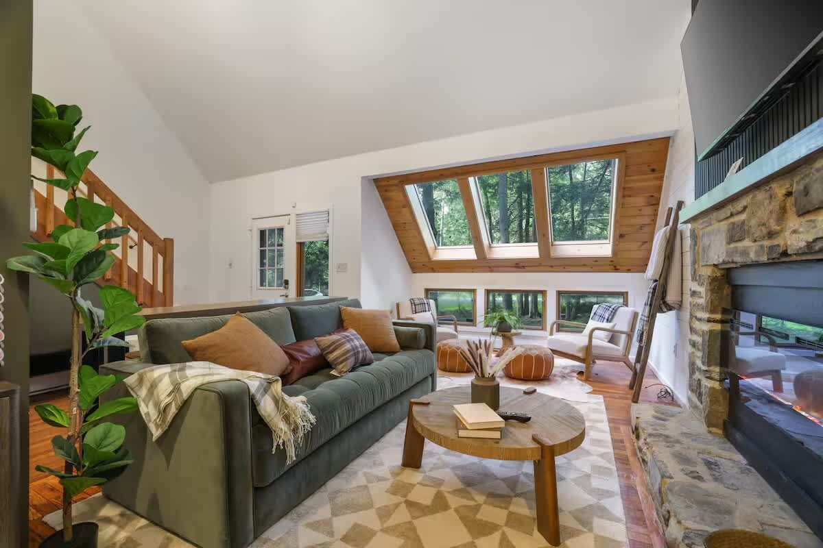 A modern living room with a green sofa, a round coffee table, and a stone fireplace.