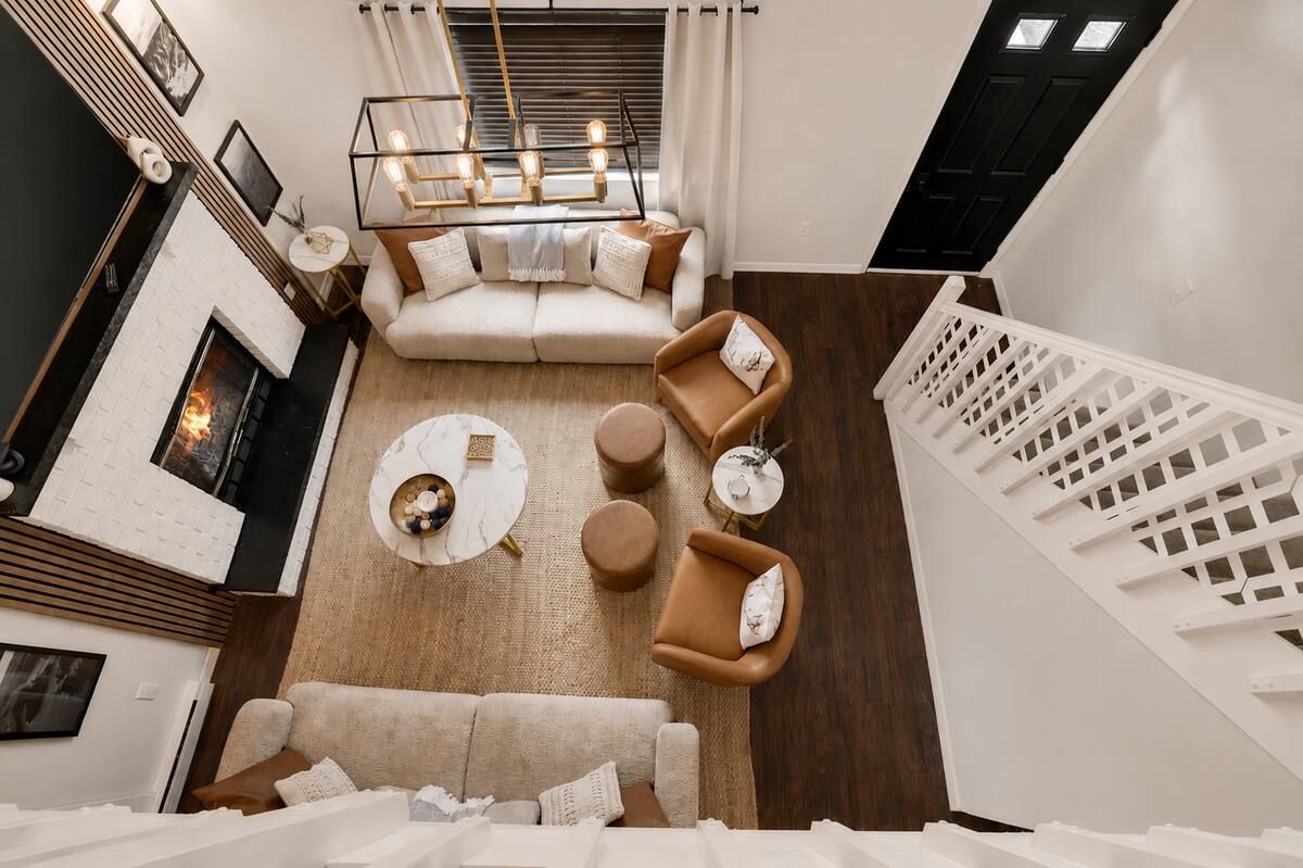 Un salon moderne avec une cheminée, un ensemble de canapés, une table basse et un escalier.