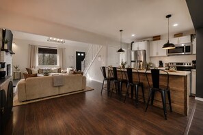 A modern kitchen with a central island, dark wooden flooring, and a dining area with chairs. - Putting Green | Hot Tub | Sauna | Theater | Arcade (Coolbaugh Township)