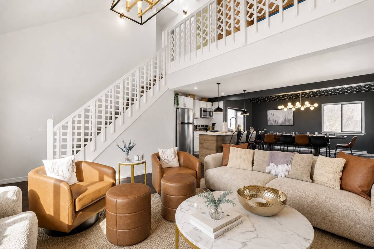 A modern living room with a staircase, a dining area, and a kitchen.