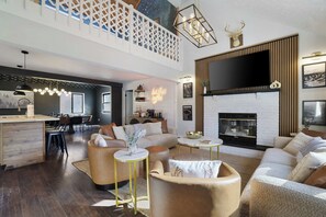 A spacious living area with a high ceiling, a fireplace, and a large TV mounted on the wall. - Putting Green | Hot Tub | Sauna | Theater | Arcade (Coolbaugh Township)