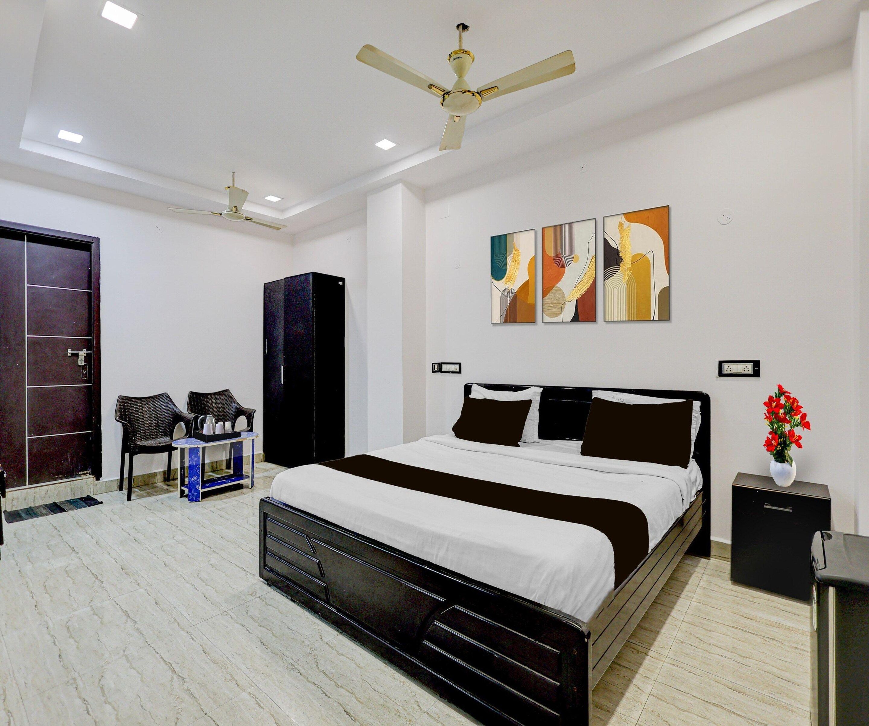 A modern bedroom with a large bed, a ceiling fan, artwork on the wall, and a wardrobe.