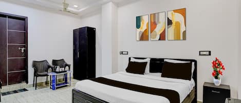 A modern bedroom with a large bed, a ceiling fan, artwork on the wall, and a wardrobe.