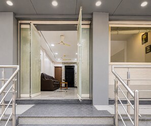 Un interior moderno con una escalera que lleva a una sala de estar, un sofá y un ventilador de techo.