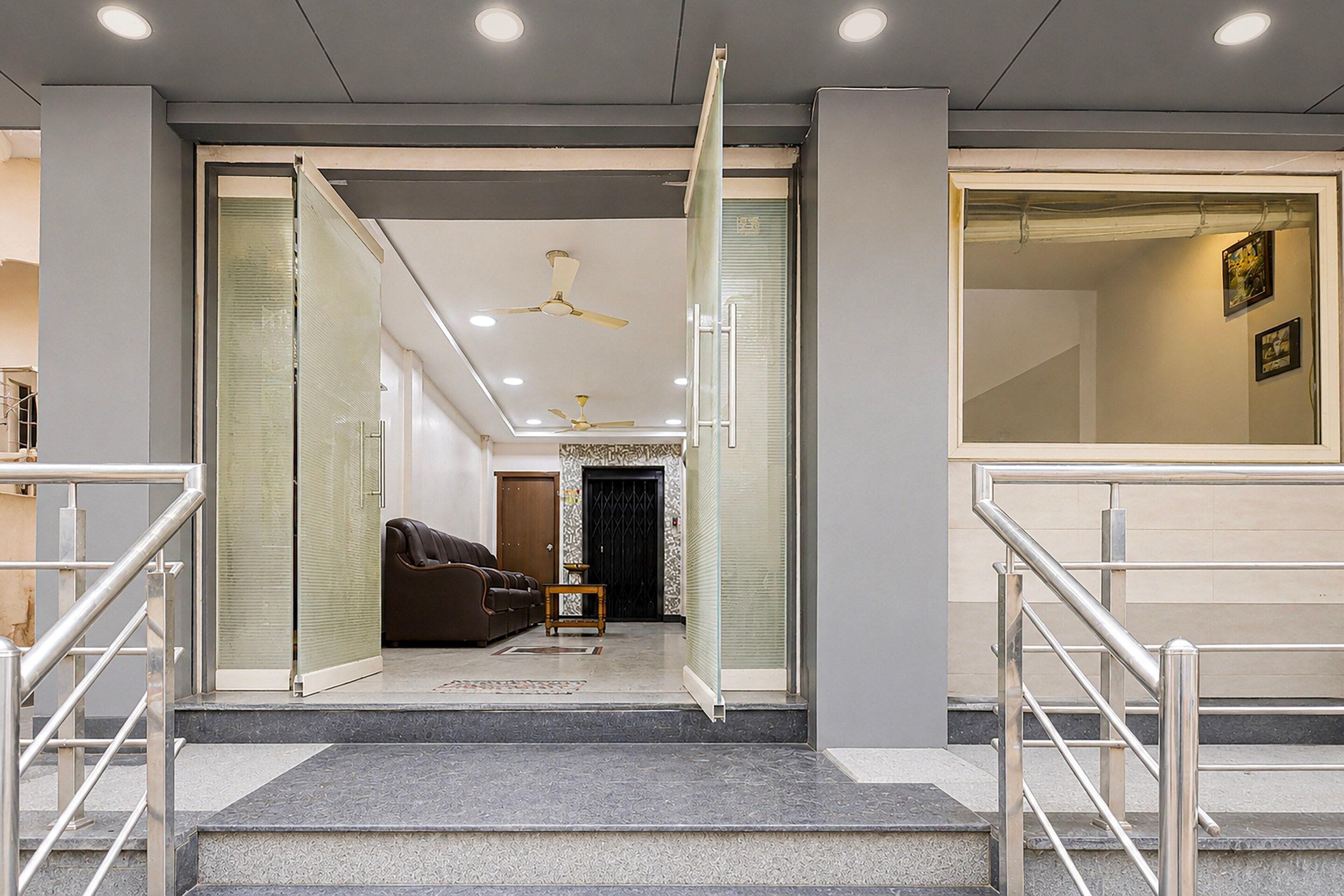 Un vestíbulo de hotel con una escalera, un sofá y un ventilador de techo.