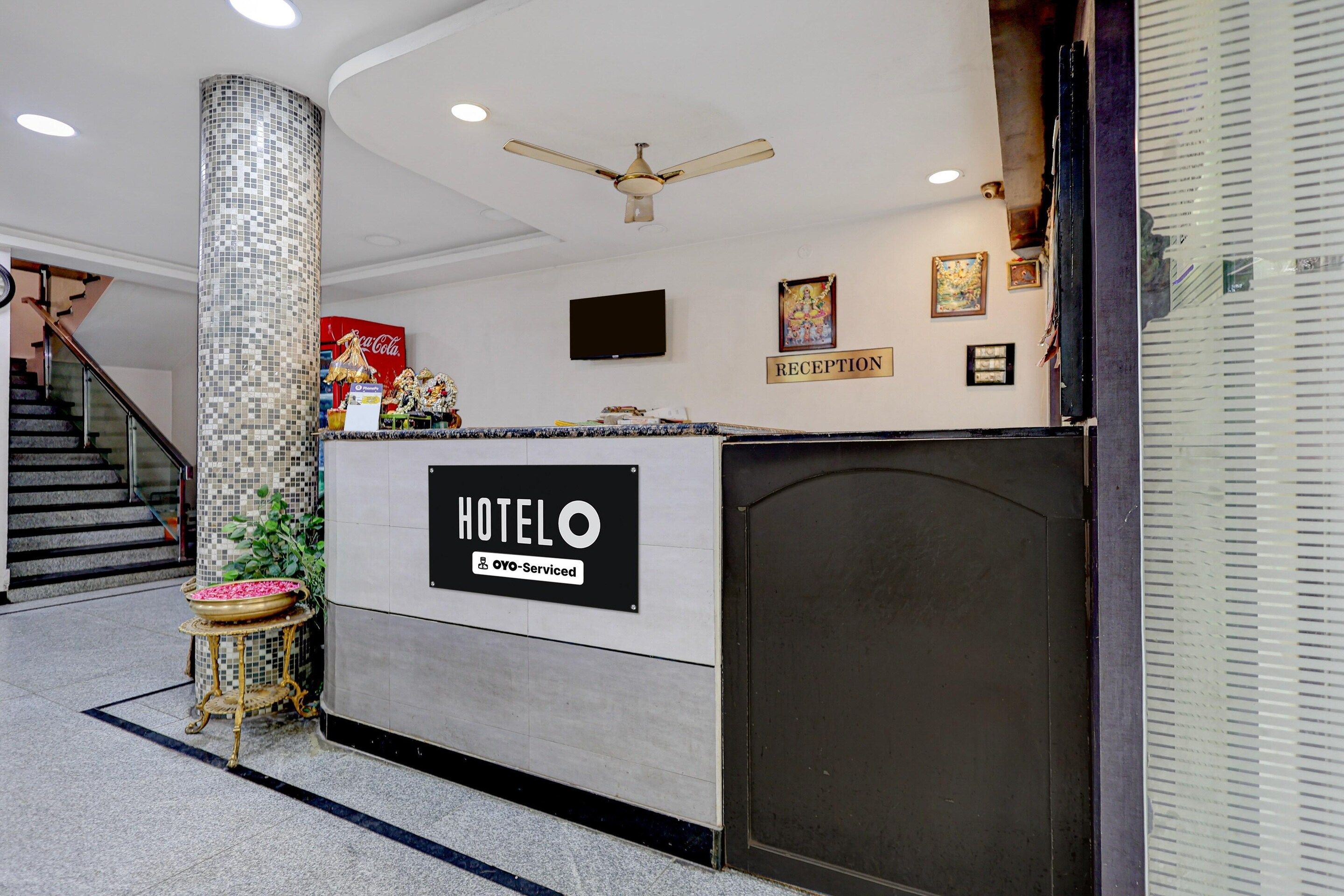 A hotel reception area with a reception desk, a Coca-Cola sign, a television, and a staircase.