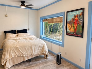 A bedroom with a bed, a window with a view of bamboo, a poster of Atlantic City, and a ceiling fan. - Nashville's Famous Loveless Cafe Stay (Nashville)