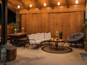 A cozy outdoor seating area with a wooden table, cushioned chairs, and a round table with candles. - Nashville's Famous Loveless Cafe Stay (Nashville)