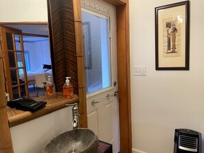 A bathroom with a wooden vanity, a stone sink, a window with blinds, and a framed picture on the wall. - Nashville's Famous Loveless Cafe Stay (Nashville)