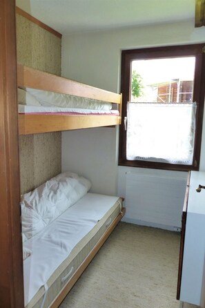 A small, compact room with bunk beds, a window, and a radiator. - Flurina / Burtscher, (Falera). 3 Zimmerferienwohnung für max. 4 Personen, am ge by Interhome (Falera)