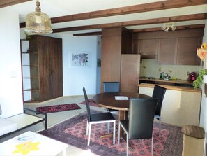 A dining area with a table and chairs, a kitchen with cabinets, and a hanging light fixture. - Flurina / Burtscher, (Falera). 3 Zimmerferienwohnung für max. 4 Personen, am ge by Interhome (Falera)