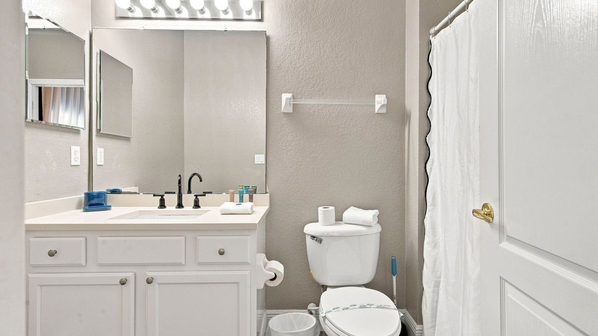 Une salle de bain avec un lavabo blanc, un miroir et des toilettes.