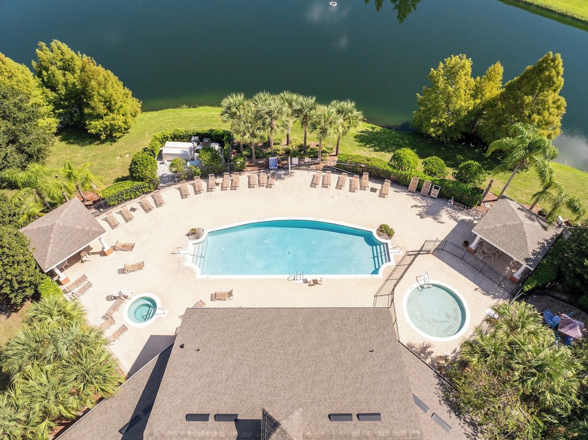 An aerial view of a resort with a large swimming pool, lounge chairs, and a hot tub.