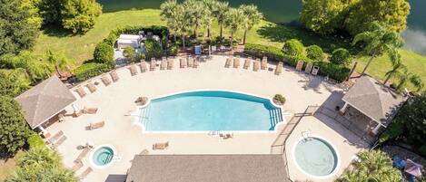 An aerial view of a resort with a large swimming pool, lounge chairs, and a hot tub.
