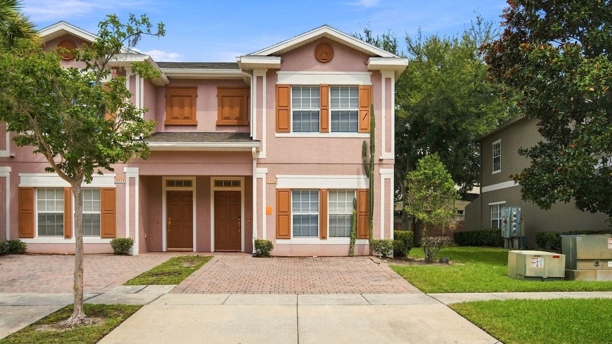 A two-story residential building with a symmetrical facade, a central entrance, and a brick driveway.
